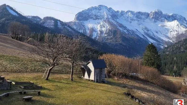 Idyllischer Gartenbereich mit Feuerstelle und Blick auf die schneebedeckten Berge.