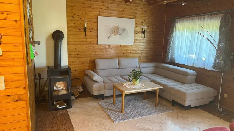 Gemütliches Wohnzimmer mit Holzvertäfelung, Kaminofen und bequemer Sitzecke.