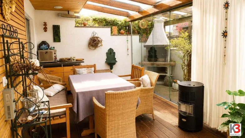 Gemütlicher Wintergarten mit Essbereich, Holzboden, Glasdach und integriertem Grillbereich hinter Glas.