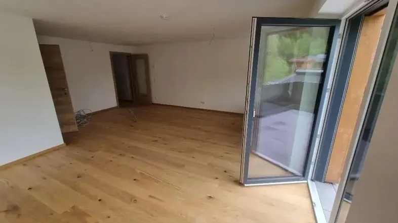 Geräumiges, helles Zimmer mit Holzboden und Zugang zu einem Außenbereich, ideal für Wohnzwecke.