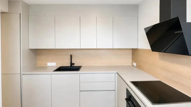 Moderne Küche mit hellgrauen Schränken, schwarzer Spüle und Induktionskochfeld, ergänzt durch eine Holzrückwand.