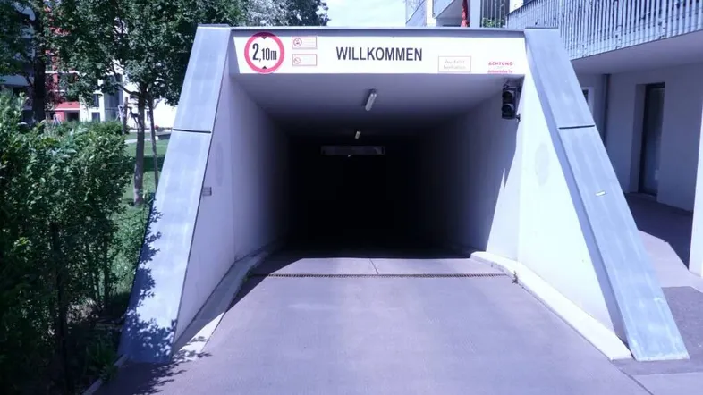 Einfahrt zur Tiefgarage mit Höhenbegrenzung von 2,10 Metern und Willkommensschild.