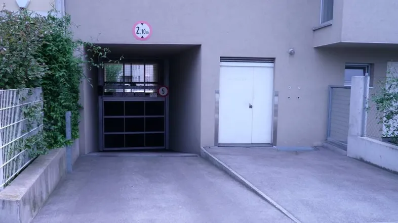 Eingang zu einer Tiefgarage mit einer Höhenbegrenzung von 2,10 Metern und einer Rampe.
