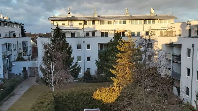 Blick von oben auf einen Innenhof mit Spielplatz und umliegenden Wohngebäuden unter bewölktem Himmel.