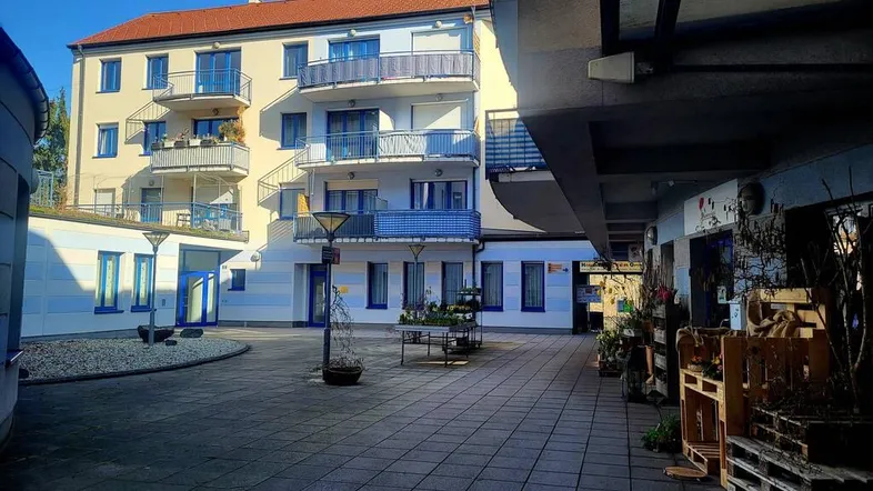 Blick auf den Innenhof eines Wohngebäudes mit mehreren Balkonen und gepflastertem Bereich.