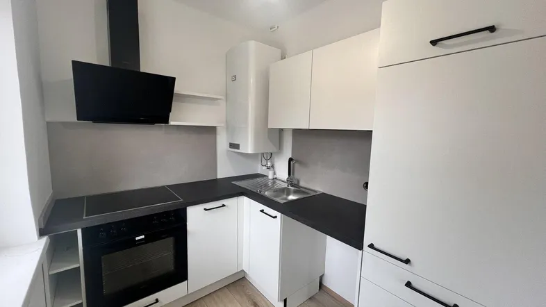 Moderne Einbauküche mit weißen Schränken, dunkler Arbeitsplatte und integrierten Geräten.