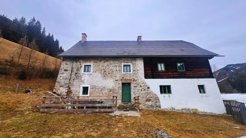 Historisches Bauernhaus mit Steinfassade und Holzelementen in ländlicher Umgebung.