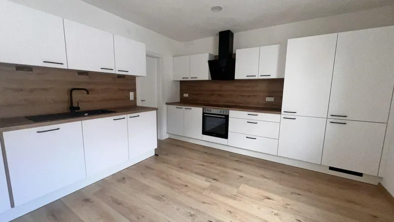 Moderne Einbauküche mit weißen Fronten, Holzoptik-Arbeitsplatten und integrierten Geräten.