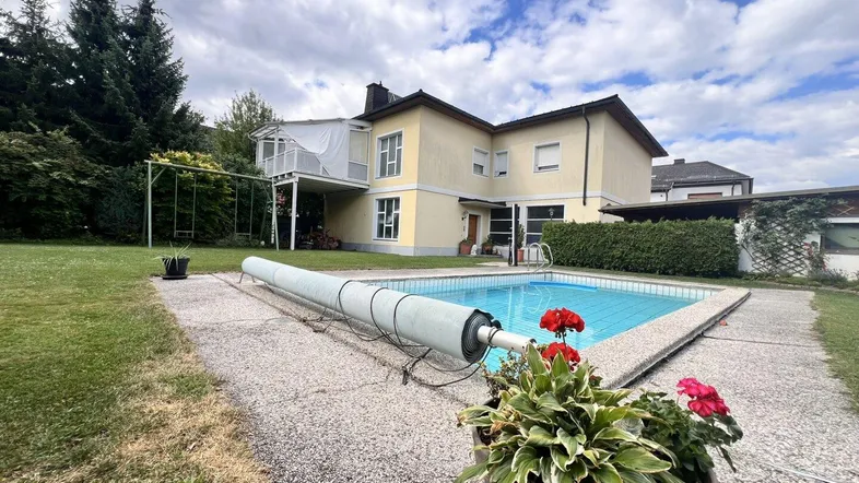 Großzügiger Gartenbereich mit Swimmingpool, Rasenfläche und Schaukel im Freien.