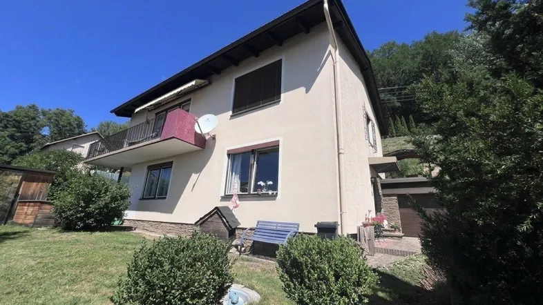 Einfamilienhaus mit Balkon und Garten in sonniger Hanglage und grüner Umgebung.