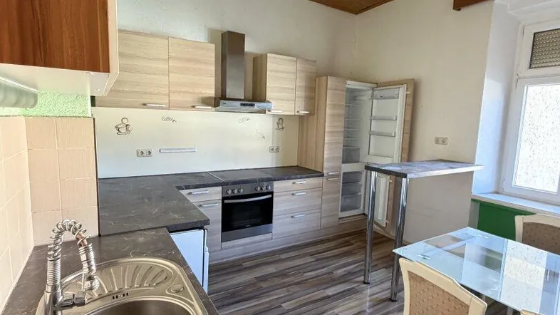 Helle Küche mit Holzdecke, Laminatboden und Essbereich, ausgestattet mit Einbaugeräten.