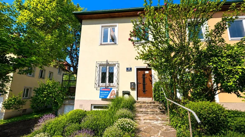 Vorderansicht des Hauses mit gepflegtem Vorgarten und Steintreppe zum Eingang.