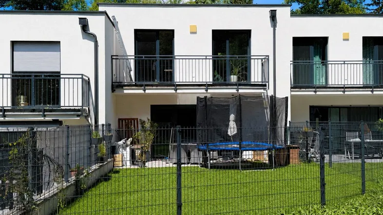Moderne Reihenhäuser mit privaten Gärten und Balkonen, umgeben von grüner Natur.