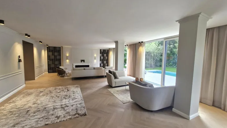 Geräumiges, helles Wohnzimmer mit modernem Interieur, Fischgrätparkett und Zugang zum Garten mit Pool.