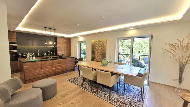 Moderne offene Küche mit Essbereich, Holzboden und indirekter Deckenbeleuchtung.
