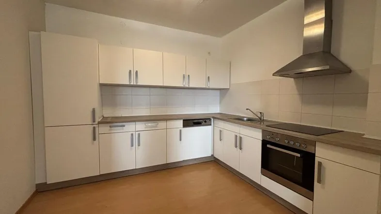 Moderne Einbauküche mit weißen Schränken, Holzarbeitsplatte und integrierten Geräten, ideal für den täglichen Gebrauch.