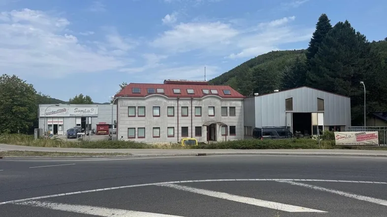 Gesamtansicht des Gewerbekomplexes mit Bürogebäude und Lagerhallen an einer Straße.