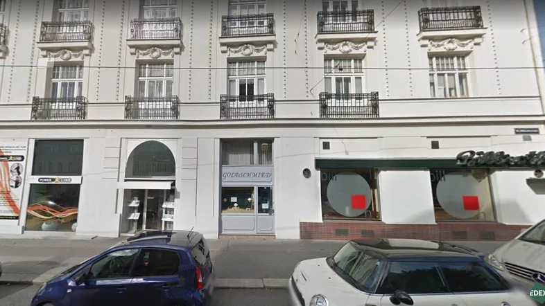 Klassische Fassade eines Mehrfamilienhauses mit Geschäften im Erdgeschoss und Balkonen in den oberen Etagen.