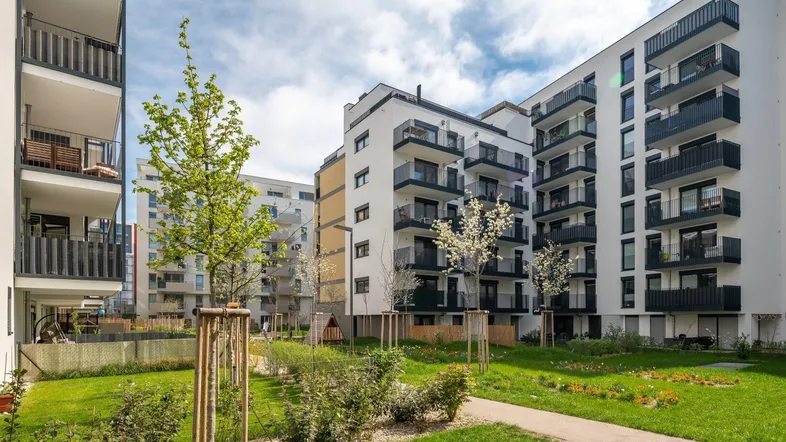 Moderne Wohngebäude mit Balkonen umgeben von einer gepflegten Grünanlage und Spielplatz.