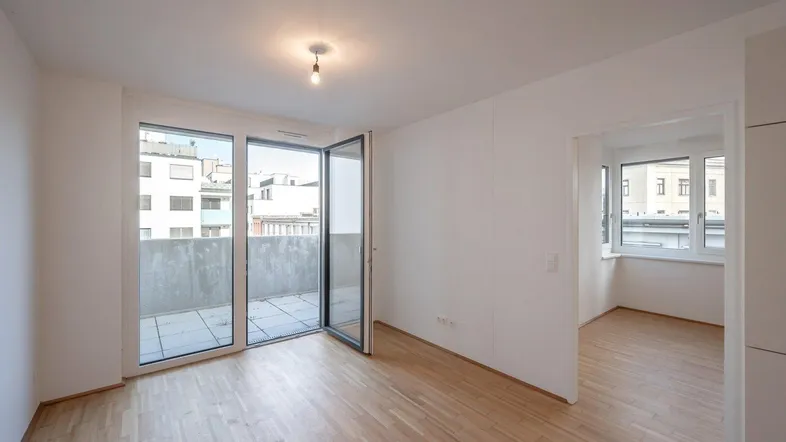 Helles Zimmer mit Parkettboden und Zugang zu einem geräumigen Balkon, ideal für entspannte Stunden.