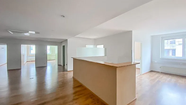 Geräumiger Bürobereich mit hellem Holzfußboden und einer Empfangstheke, ideal für offene Arbeitskonzepte.