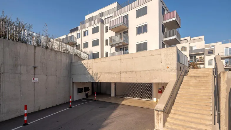 Zufahrt zur Tiefgarage und Treppenaufgang eines modernen Wohngebäudes.