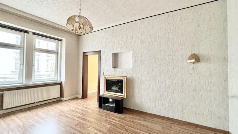 Wohnzimmer mit strukturierten Wänden, Laminatboden und klassischem Kronleuchter.