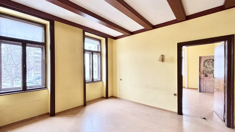 Geräumiges Zimmer mit Holzbalkendecke, gelben Wänden und Blick auf die Umgebung.