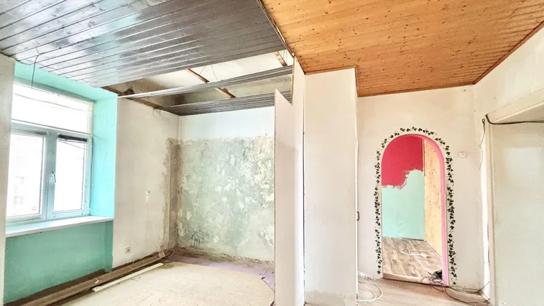 Unfertiger Innenraum mit Holzbalkendecke und Renovierungsbedarf, bereit für die Neugestaltung.