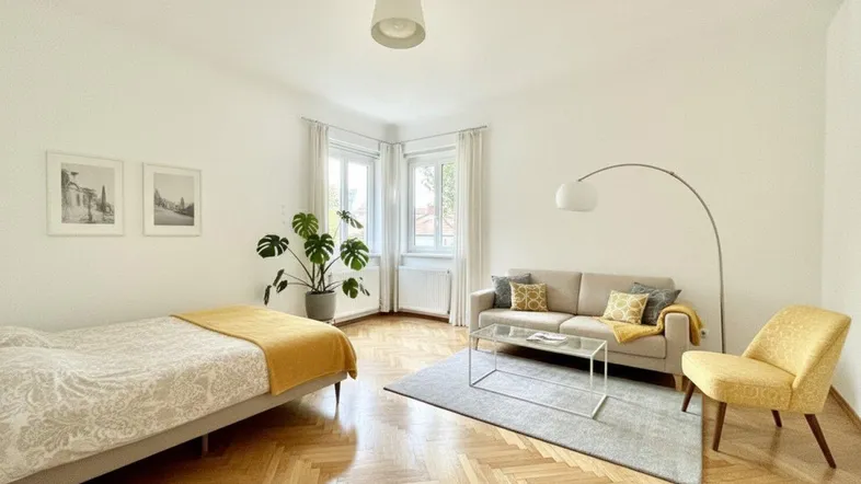 Helles Zimmer mit Fischgrätparkett, Sofa, Bett und großen Fenstern in der Ecke, modern eingerichtet.