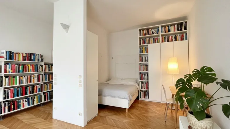 Helles Schlafzimmer mit Fischgrätparkett, integrierten Bücherregalen und moderner Einrichtung.