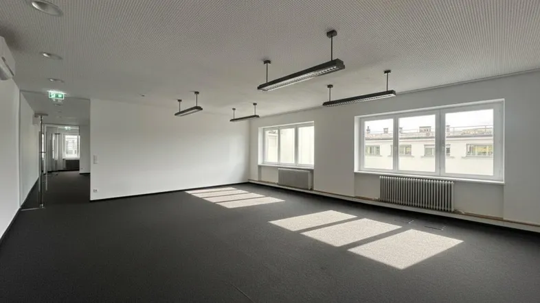 Geräumiger Büroraum mit Teppichboden, großen Fenstern und natürlichem Lichteinfall.