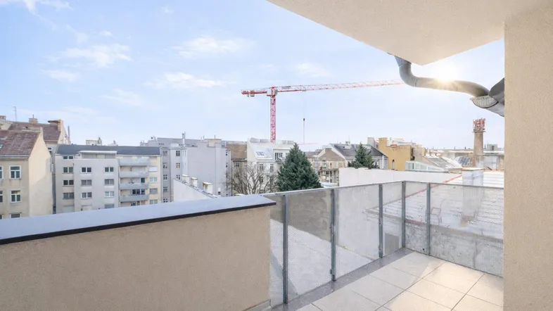 Heller Balkon mit Fliesenboden und weitem Blick über die Stadt und Baustellenkran.