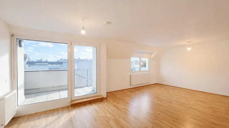 Helles Wohnzimmer mit Parkettboden, Dachschrägen und Zugang zu einer Terrasse.