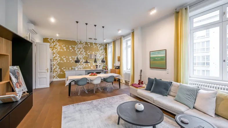 Helles Wohn- und Esszimmer mit Holzboden, moderner Einrichtung und dekorativer Tapete.