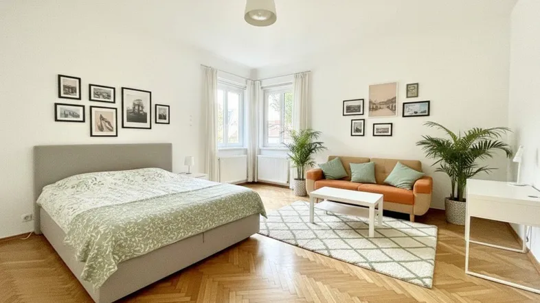 Helles Zimmer mit Fischgrätparkett, Bett, Sofa und Blick ins Grüne, modern eingerichtet.