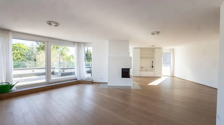 Geräumiges, helles Wohnzimmer mit Parkettboden, modernem Kamin und Zugang zur großen Terrasse.