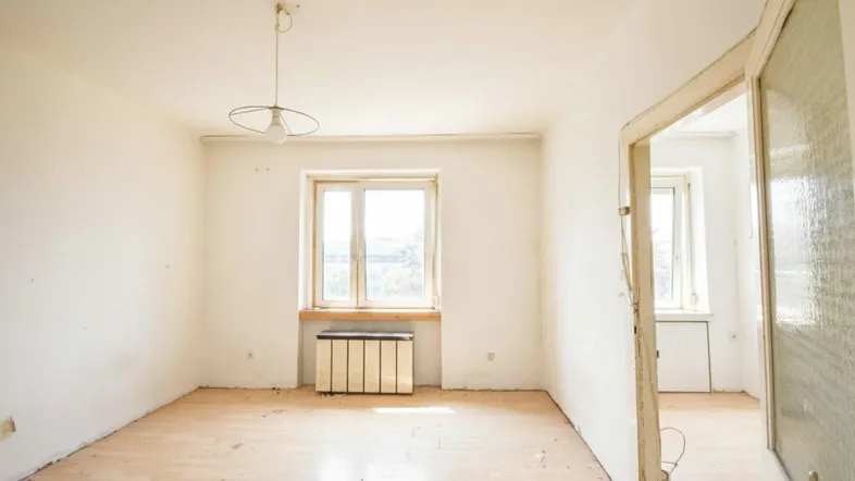 Helles, unmöbliertes Zimmer mit Holzboden und Fenster, bereit für die individuelle Gestaltung.