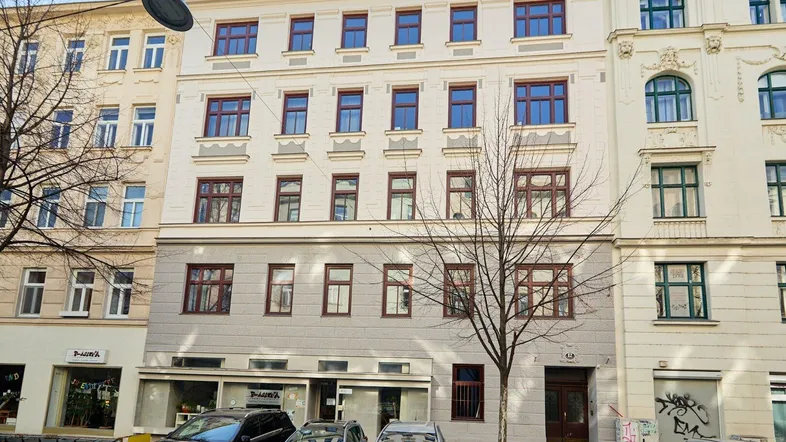 Mehrstöckiges Wohngebäude mit klassischer Fassade und vielen Fenstern an einer städtischen Straße.