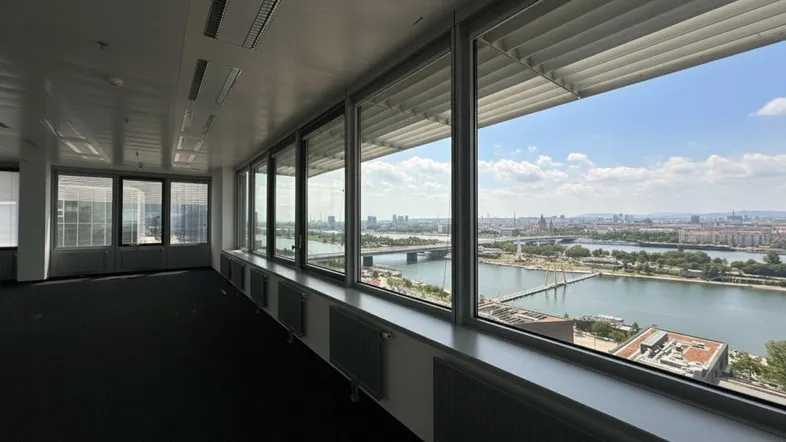 Geräumiges, leeres Büro mit großen Fenstern, die einen weiten Blick auf die Stadt und den Fluss bieten.