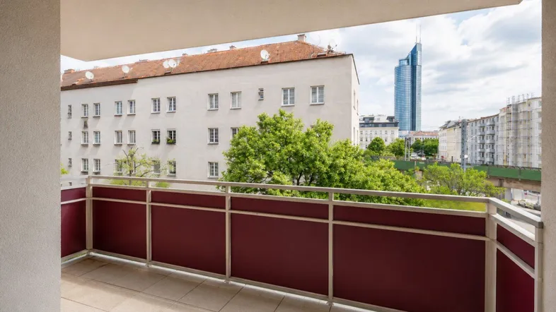 Geräumiger Balkon mit Fliesenboden und Blick auf die Stadt und moderne Hochhäuser.