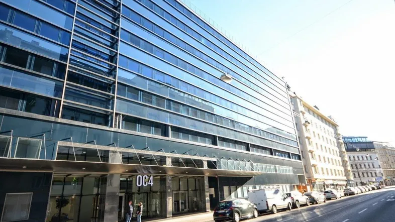 Moderne Bürogebäude-Fassade mit reflektierenden Glasflächen und klarem Himmel an einem sonnigen Tag.