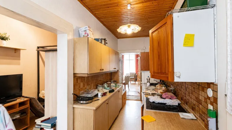 Schmale Küche mit Holzschränken, gefliestem Spritzschutz und Blick in den Essbereich.