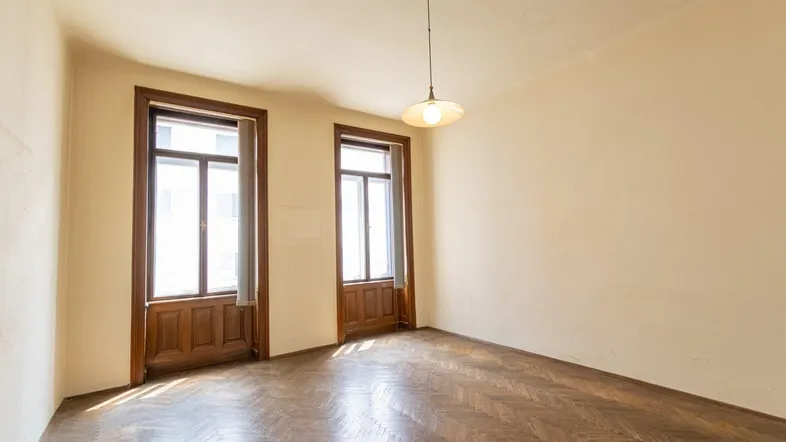 Helles Zimmer mit Fischgrätparkett und hohen Fenstern, bereit zur individuellen Gestaltung.