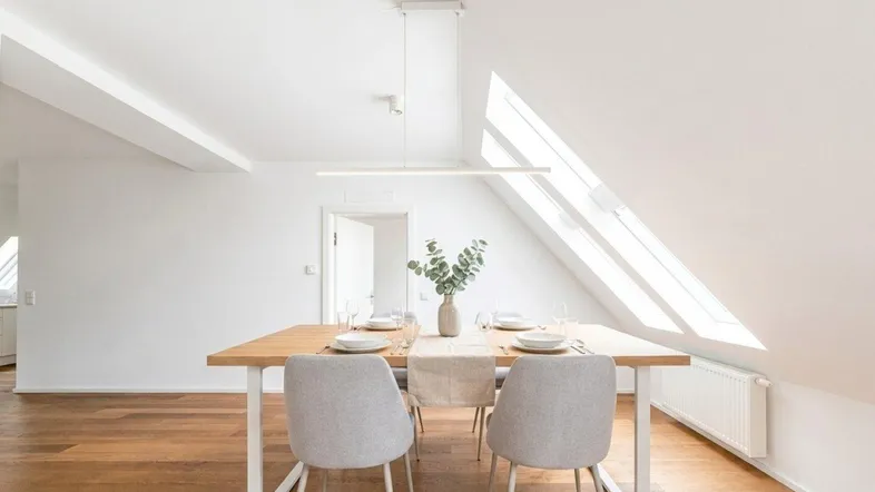 Helles Esszimmer mit Holztisch, modernen Stühlen und Dachfenstern für viel Tageslicht.