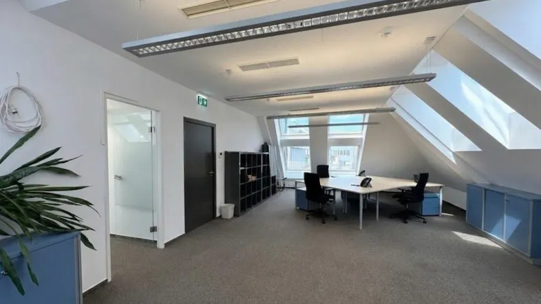 Geräumiges Büro im Dachgeschoss mit Schrägdach, Dachfenstern und moderner Beleuchtung.