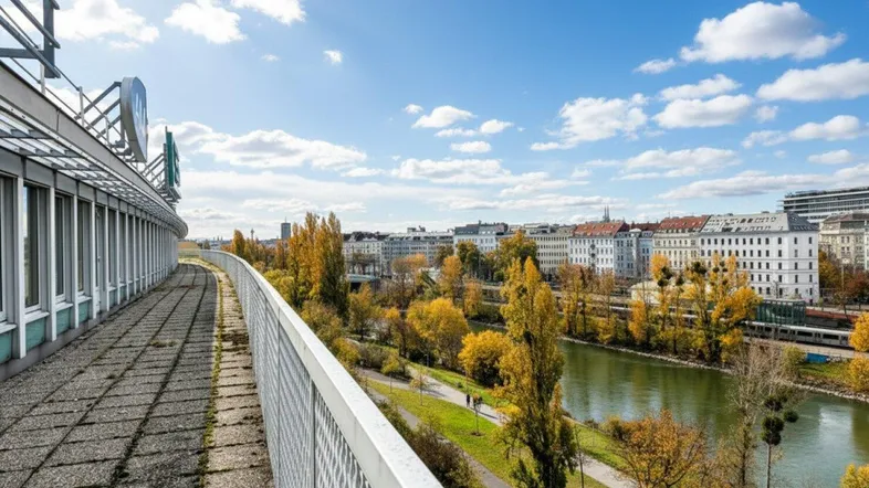 Langer Außenbereich entlang des Gebäudes mit Blick auf den Fluss, einen Park und die Stadt.