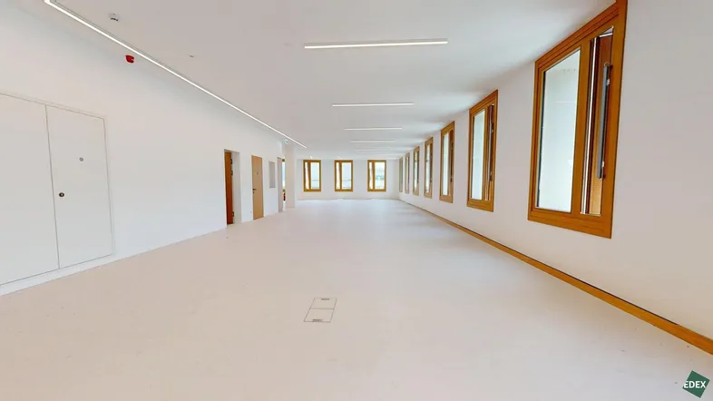 Heller, weitläufiger Gewerberaum mit zahlreichen Fenstern und moderner Beleuchtung, ideal für Büronutzung.