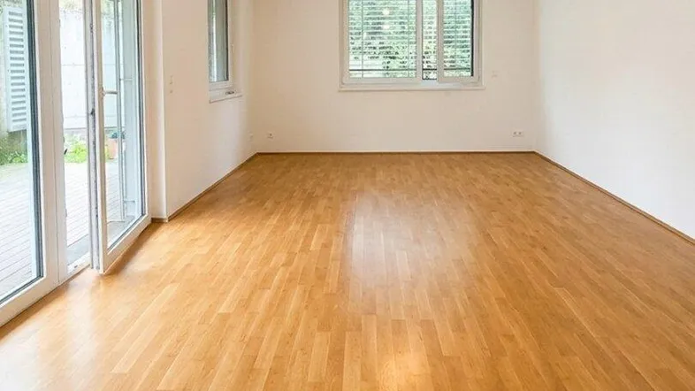 Helles Zimmer mit Holzboden und Zugang zu einer Terrasse, ideal für Wohn- oder Schlafbereich.
