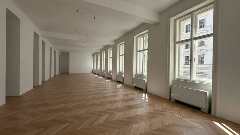 Großer, heller Raum mit Fischgrätparkett und vielen Fenstern, ideal für Büronutzung.